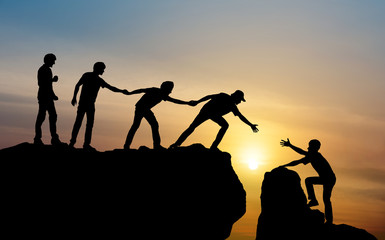 team helping each other climb mountain